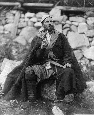 Elderly Georgian peasant seated with a dagger and a long smoking pipe