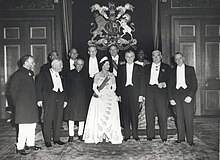 A formal group of Elizabeth in tiara and evening dress with eleven politicians in evening dress or national costume