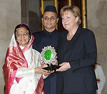 Merkel and two other people holding the Jawaharlal Nehru Award for International Understanding.