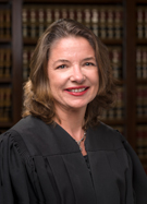Photo en buste d'une femme brune souriante et portant la tenue de magistrate américaine.