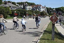 Bicyclists on a road. Houses can be seen at left.