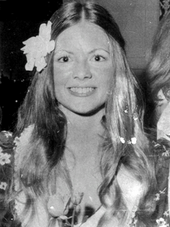 A smiling young Caucasian woman with long hair parted in the center