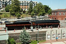 A black streamlined steam locomotive on display with the hotel and train station buildings in the background