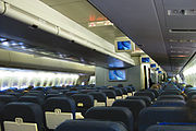 Cabine principale d'un avion avec deux couloirs et plusieurs rangées de sièges.