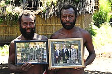 Deux hommes noirs montrant des photos dans des cadres.
