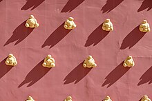 Eight sunlit triangular loaves of bread on a red wall.