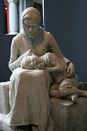 Sculpture représentant une femme assise, un enfant la tête sur ses genoux, observant cet enfant de façon anxieuse