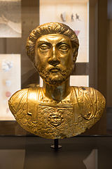 Buste en or d'un homme barbu aux cheveux frisés portant une cuirasse.