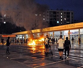 Véhicule en feu devant un centre commercial, dans le quartier de Planoise, à Besançon.