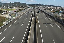 画像左 : 新東名として2012年に開通した静岡県区間の島田金谷IC付近。ICやSA等の分合流箇所では付加車線追加として当初から片側3車線で運用[24]。画像右 : 岡崎SA付近。愛知県区間は用地は往復6車線で取得済みだが構造物は往復4車線仕様[39]。このため静岡県区間と比べると幅員は狭い。
