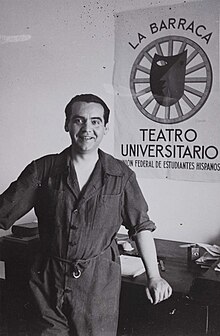 Federico García Lorca smiling, standing in front of a theater poster