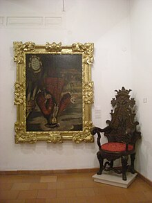 A full-body portrait of the king in an elaborate frame is displayed next to an antique chair.