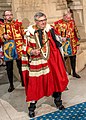現在の紋章院総裁の第18代ノーフォーク公爵エドワード・フィッツアラン＝ハワード。 総裁の服飾の上に、議会用ローブを羽織る。後方に紋章官を従える。