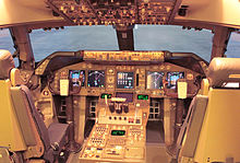 Cockpit d'un avion de ligne moderne montrant des affichages et instruments numériques. La lumière entre à travers le pare-brise.