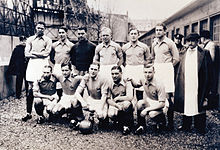 Photographie en noir et blanc d'une équipe de football prenant la pose avec un ballon dans une allée.