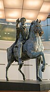 Statue d'un homme sur un cheval, tendant le bras droit en avant, de couleur grise et dorée.