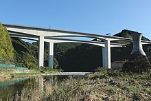 画像左 : 新安倍川橋と葵大橋。長さ1.7 kmのこの橋は県道と第二東名の二層構造で、画像奥の川岸に新静岡ICが敷設されている。インターを市街地から大きく外れた場所に造ったために新たな道路が必要になり、道路が増殖を続ける構図であるとして批判された[184]。別のマスコミはこの橋を皮肉を込めて「土木技術の展覧会の面もある」と書いた[185]。 画像右 : 静岡市清水区和田島に架かる興津川橋。200以上の橋梁建設に関わってきた建設作業員は、山の中でこうした大きい橋を造るのは初めてで驚いたという[183]。この橋の一山向こうに掘削された清水第三トンネルは公団が「第二東名の技術の結晶」と呼び、このトンネルの嘱託実験を請け負った大学教授が「唯一残った大規模な実験場だ」というインタビュー内容を皮肉交じりに記事化した[183]。