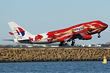 Un avion de ligne au décollage avec un fuselage rouge et blanc.