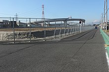 整備計画区間における起点の海老名南JCT付近。 画像左 : 住宅街に囲まれた更地である東京方面の本線建設用地最東端からジャンクションを望む。これより東（画像手前）の区間は基本計画以下にとどまっている。画像右 : 海老名南JCTに連結する相模川橋。橋脚は将来の拡幅が困難であることから完成形の片側3車線とランプ部を含めた仕様であるが[34]、その先の横浜、東京方面に延伸する目処は立っていない。