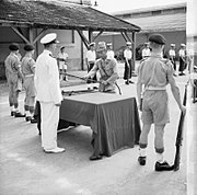 英國陸軍軍官安東尼·馬丁（Anthony Martin）於西貢（今越南胡志明市）舉辦的投降儀式上接收1名日本軍官所遞交的軍刀。