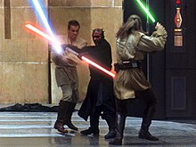 Three men fight with laser swords in a hangar.