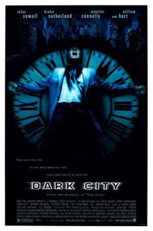 A black poster. Above reads the lines: "Rufus Sewell", "Kiefer Sutherland", "Jennifer Connelly", "and William Hurt". In the center, against a black background, a man wearing a blue jacket is rested against an upright clock with roman numerals as big as him; the setup cast in a blue tint. His arms are outspread, and his head is tilted back with his mouth agape. Behind the man and the clock is a dark city skyline. Below them is the tagline, "They built the city to see what makes us tick. Last night one of us went off." Below the tagline is the film title, "Dark City".